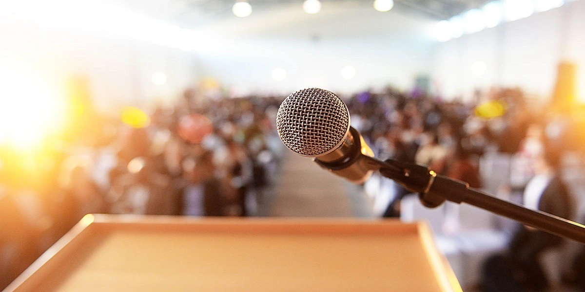 Facing microphone in front of crowd for press release