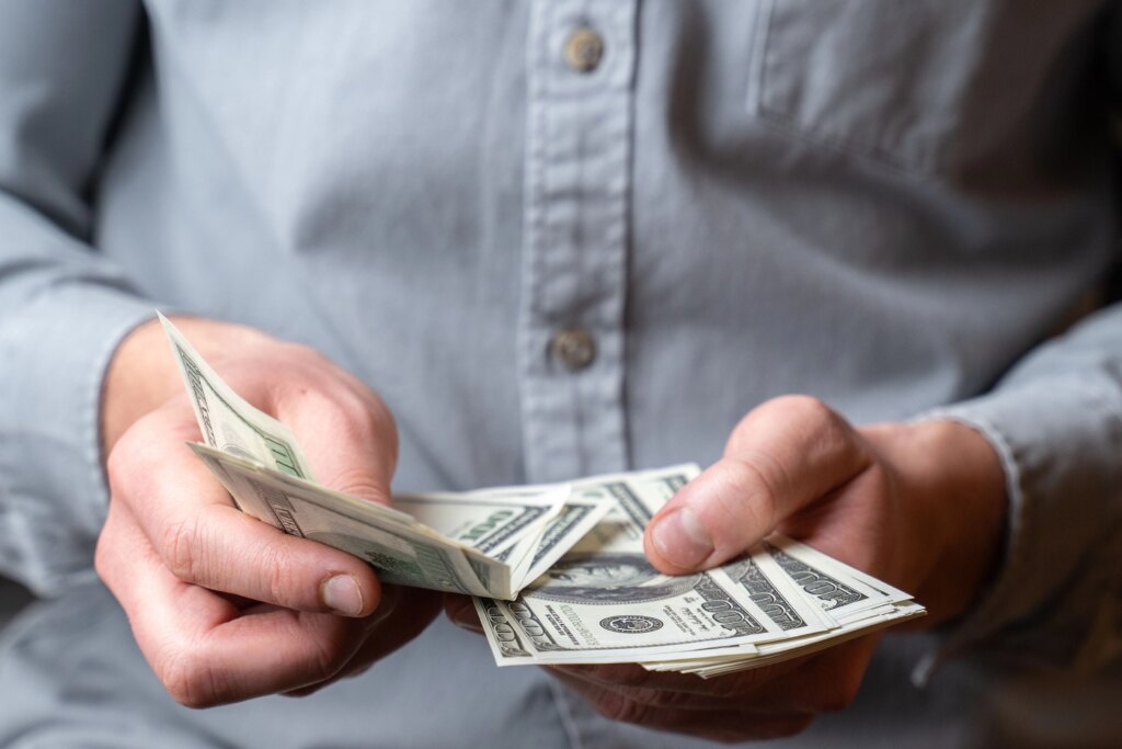 hands counting a stack of American dollar bills