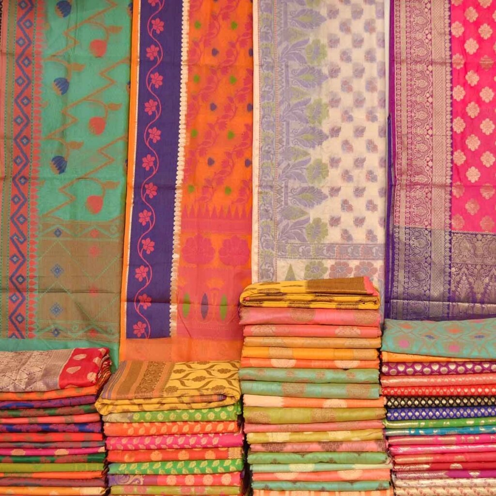 several colorful Indian textiles hanging and folded