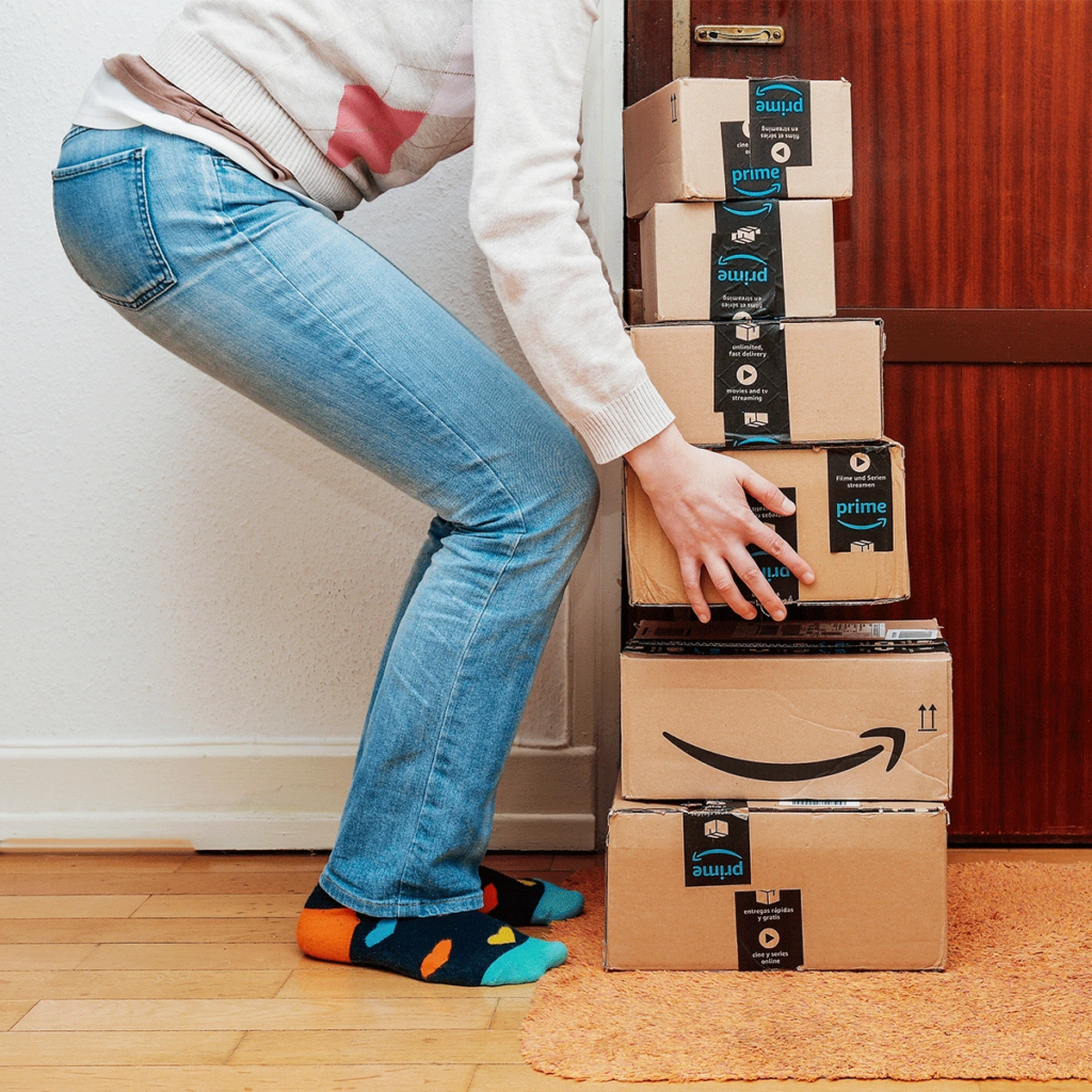 woman picking up stack of amazon fba delivery boxes packages