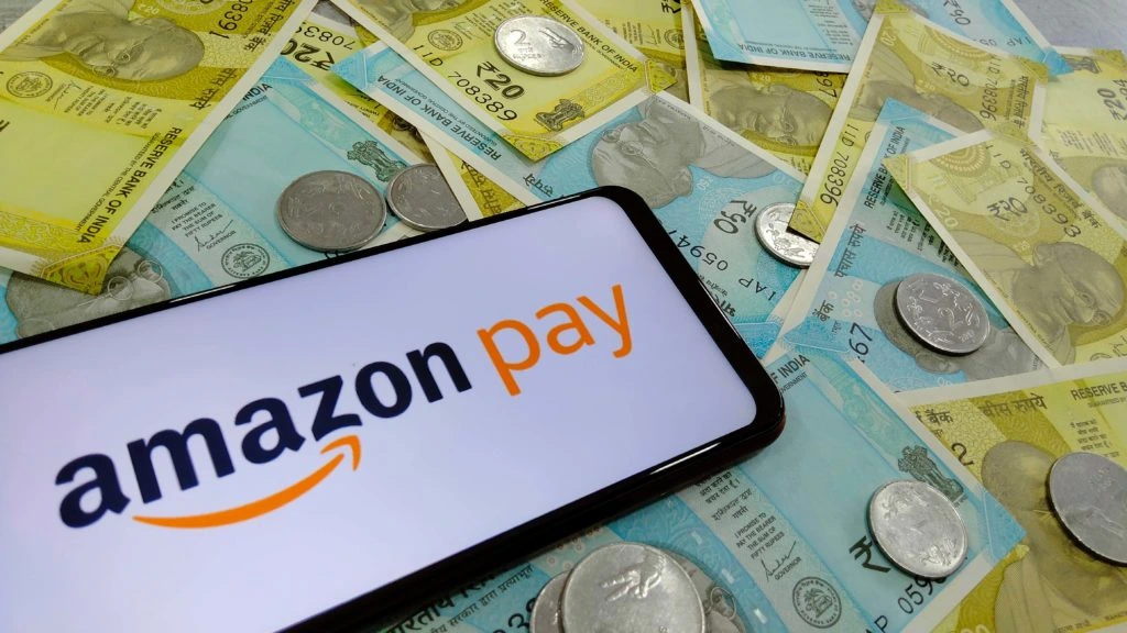 Smartphone displaying "Amazon Pay" logo on top of Indian rupee bills and coins