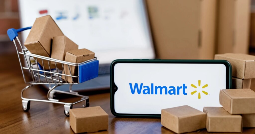 Walmart app on a smartphone and a miniature shopping cart with packages spilling out 